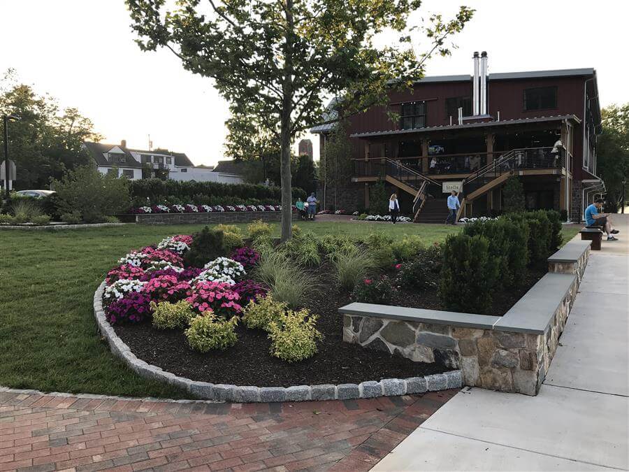 Flowers, bushes, and trees in a mulched area outside a restaurant