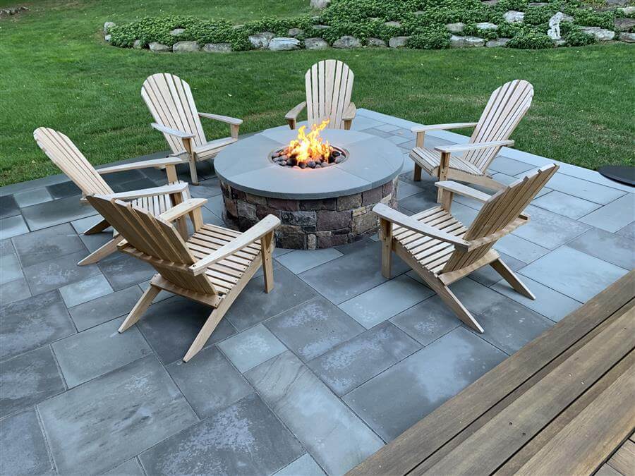 A hardscaped patio with a stone firepit surrounded by chairs
