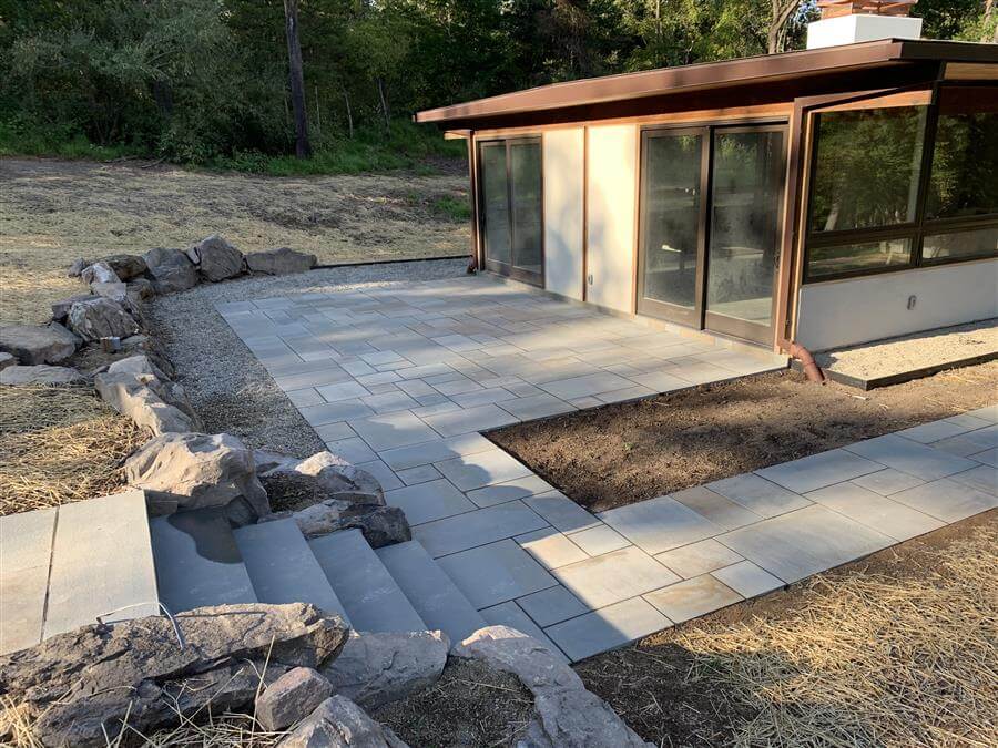 A hardscaped patio outside a brown house
