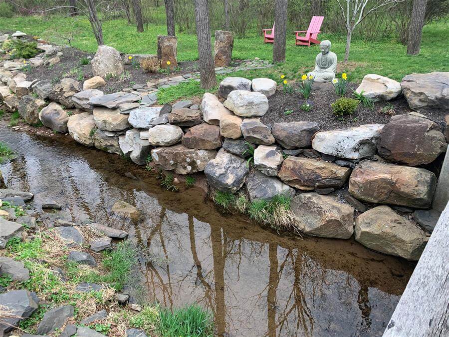 A stone wall lining a small creek
