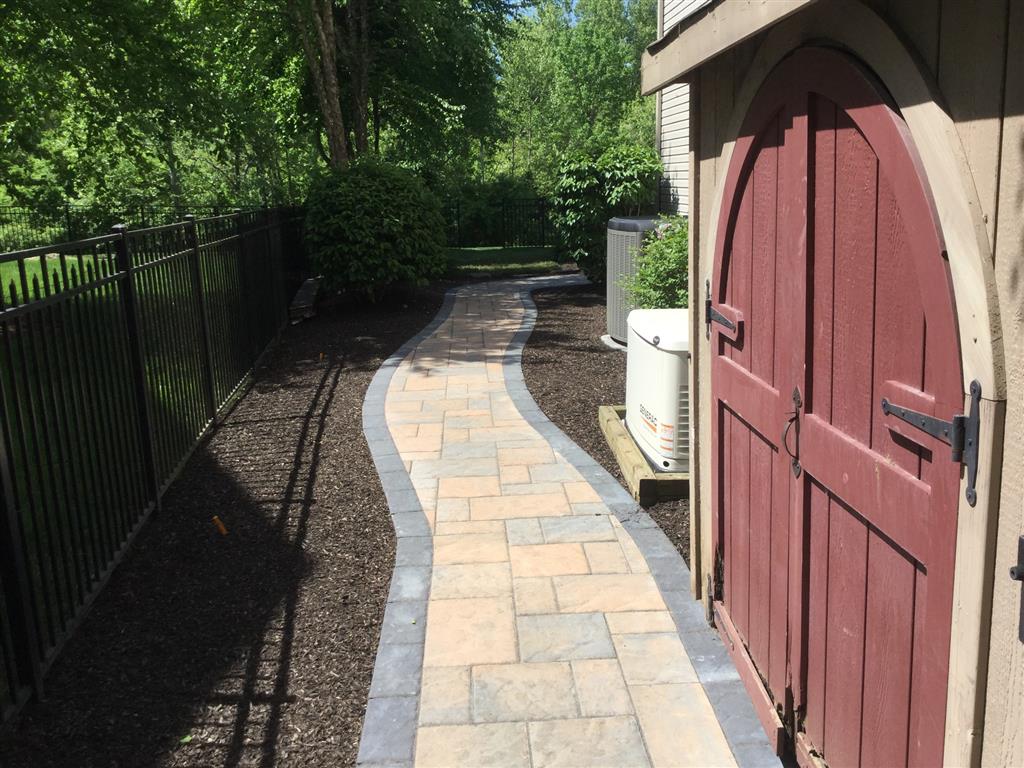 A stone walkway outside a house with a red door