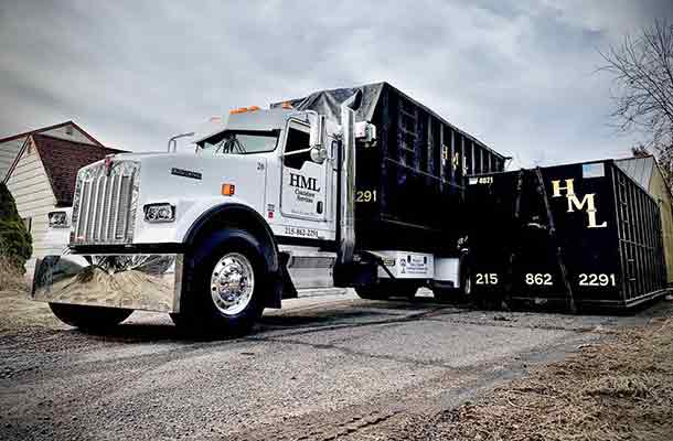 An HML Container Services truck delivery a dumpster